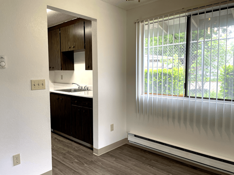 A kitchen with white walls and wooden cabinets.