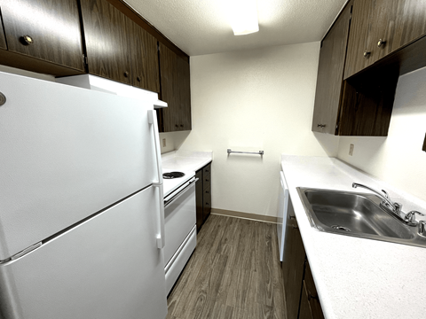A white refrigerator is in a kitchen with wood cabinets.