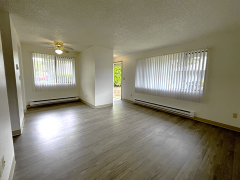 A room with a ceiling fan and two windows with blinds.