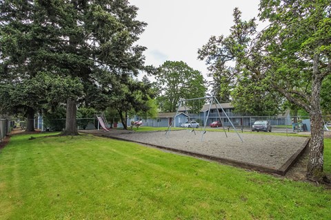 A playground with a swing set and a slide in the background.
