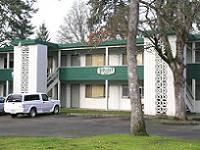 A white car is parked in front of a green and white building.
