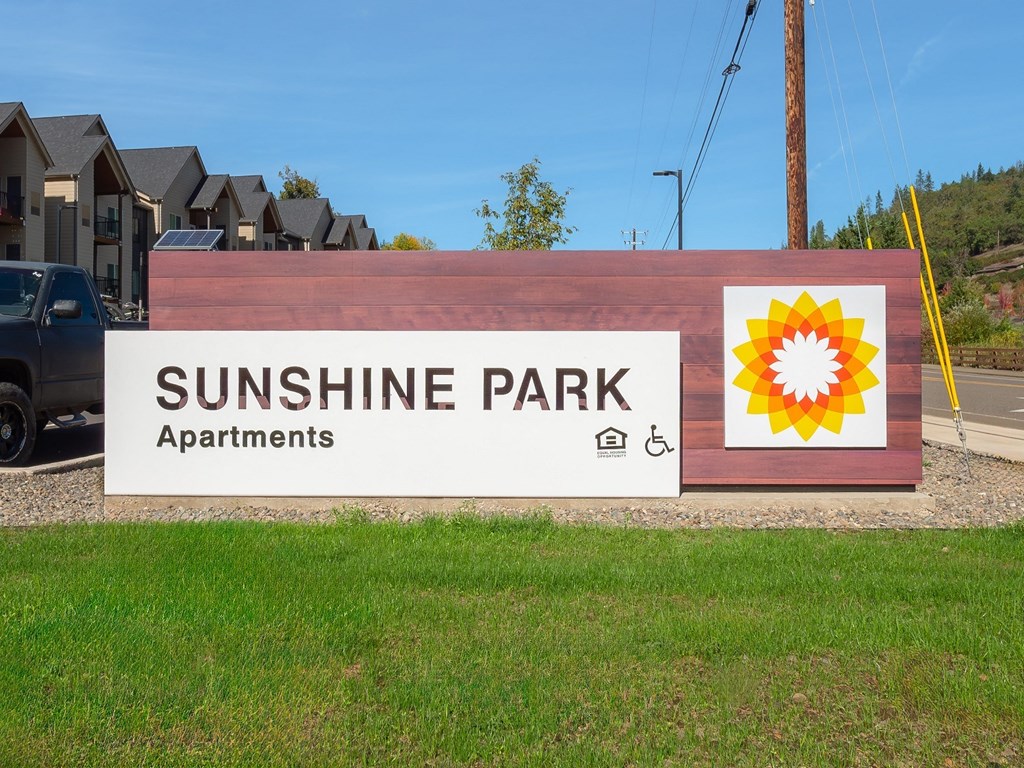 a sign for sunshine park apartments with a sunflower on it