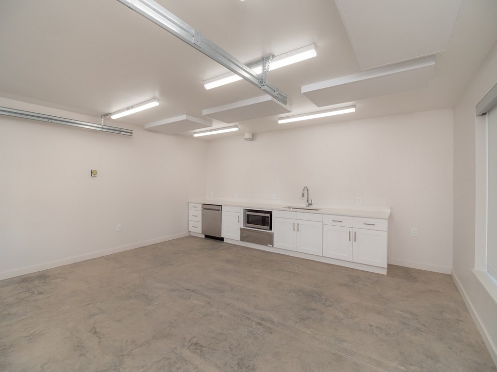 the interior of an empty room with white cabinets and a counter top and a sink
