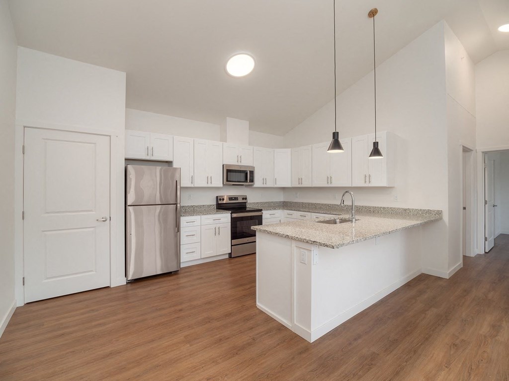 an empty kitchen with white cabinets and a counter top