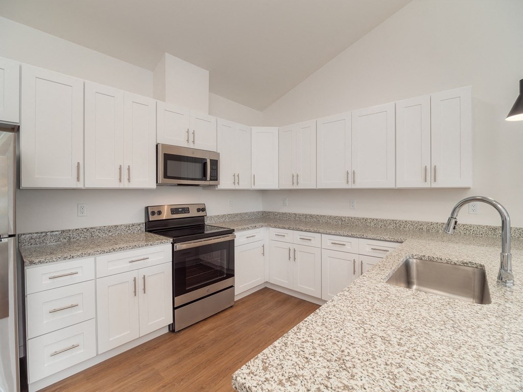 a kitchen with granite counter tops and white cabinets