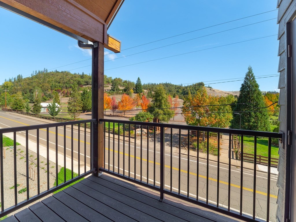 the view from the balcony of a house overlooking a street and trees