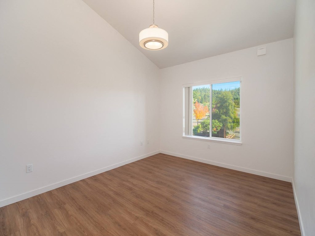 an empty living room with wood floors and a window