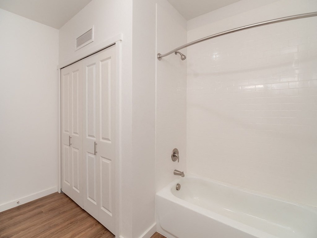 a bathroom with a white tub and shower and a white door