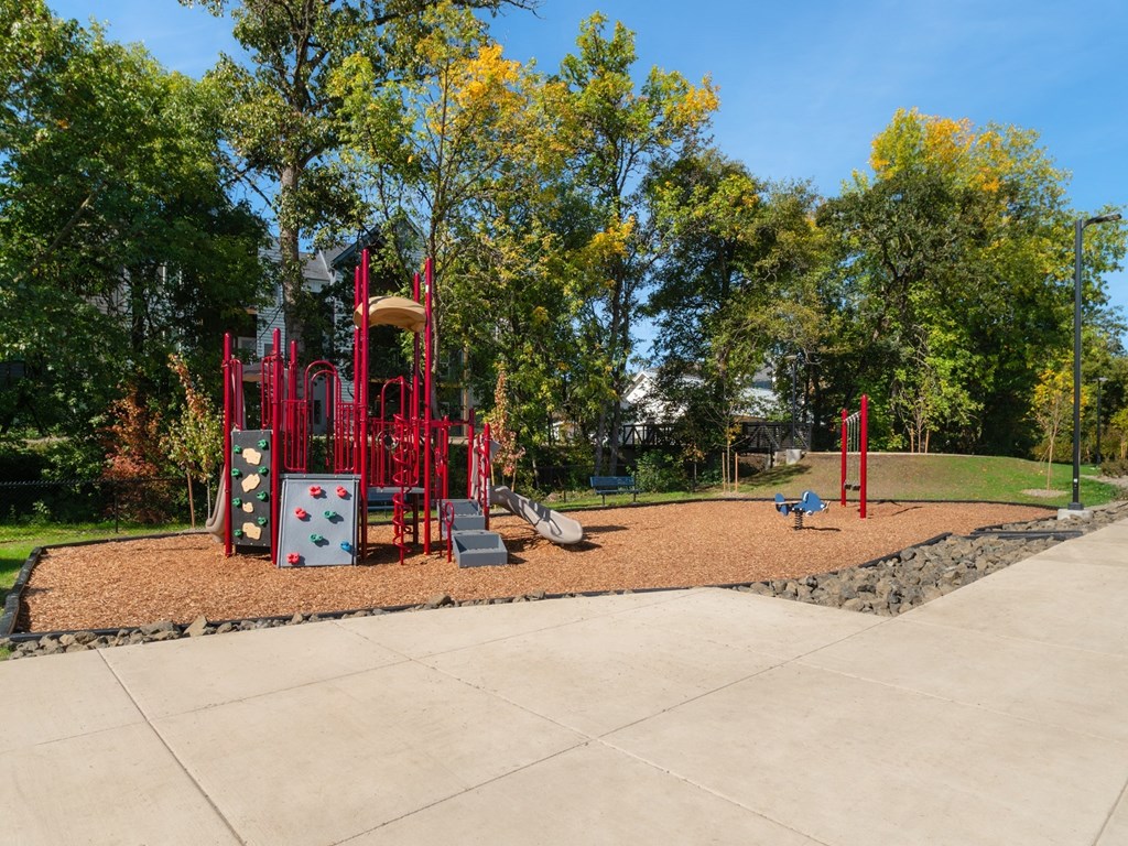 a playground with a red playset in a park