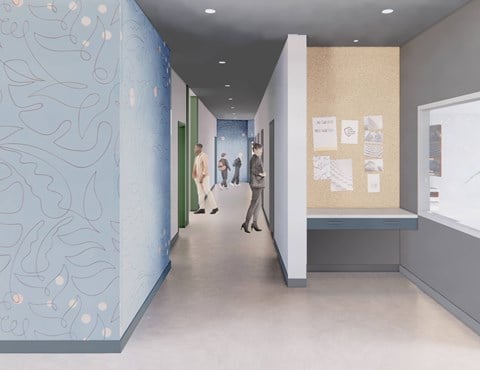 A hallway with people walking and a wall with pictures on it.