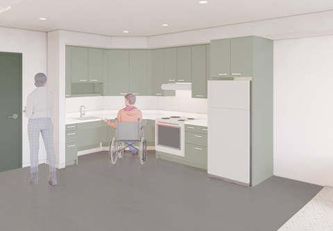 A person in a wheelchair is in a kitchen with green cabinets.