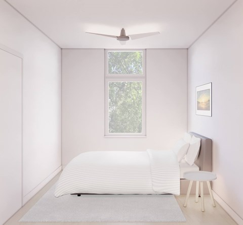 A white bedroom with a bed, chair, and window.