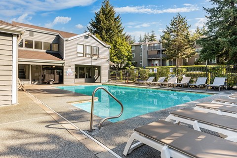 A pool with sun loungers in front of a building.