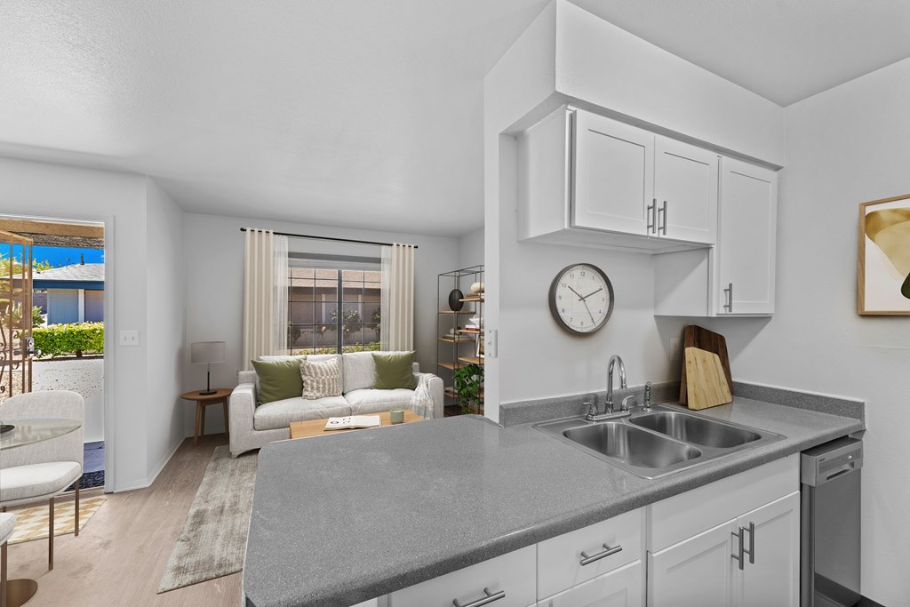 A modern kitchen with a grey countertop and white cabinets.