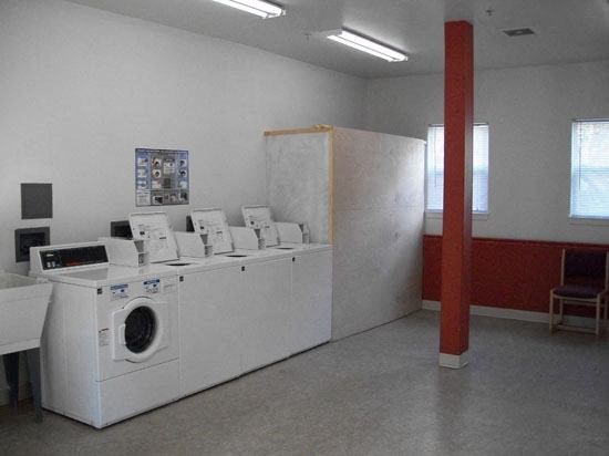 an empty laundry room with washing machines and a red pole