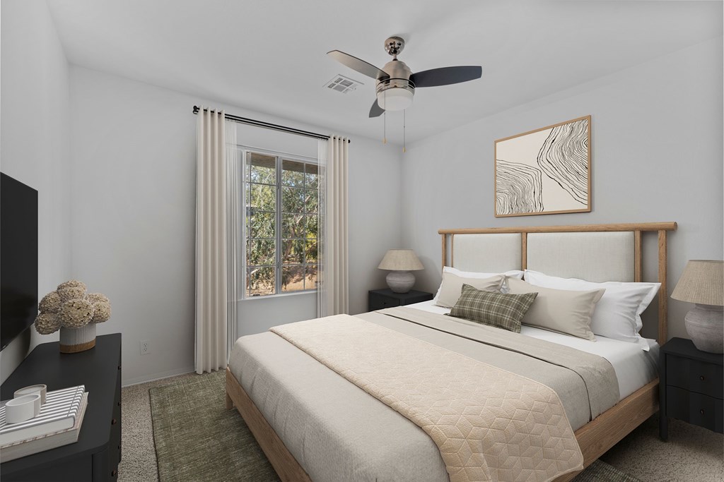 A bedroom with a large bed, a ceiling fan, and a window with curtains.