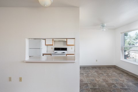 A kitchen with a fridge, stove, and oven is visible through a window.