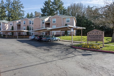 A parking lot in front of apartment buildings with a sign that says Kinnaman Apartments.