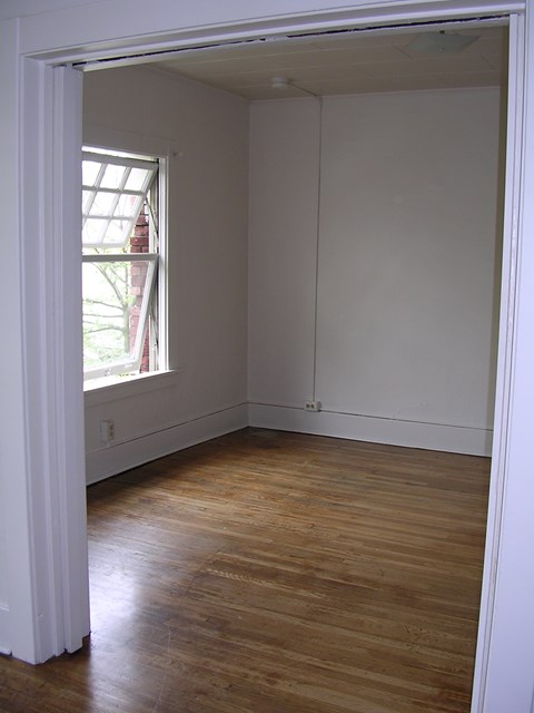 A room with a window and wooden floors.