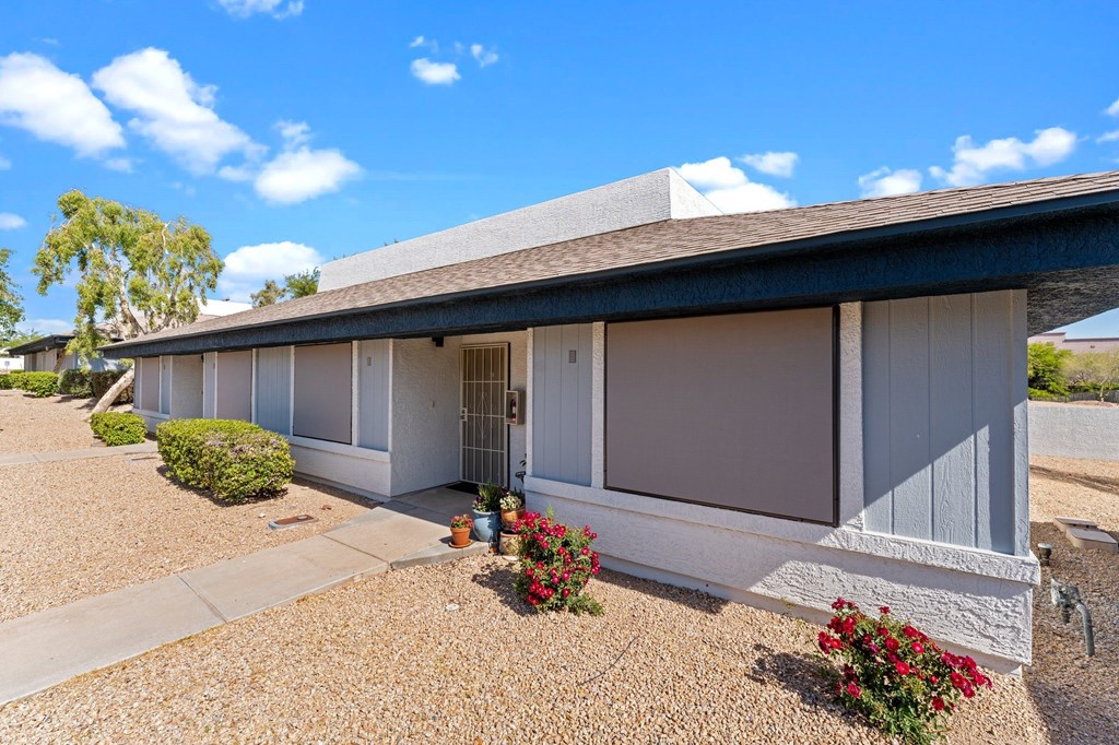A house with a grey roof and white walls with a gravel driveway in front.
