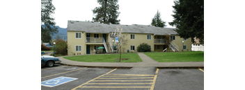 an apartment building in a parking lot with a lawn