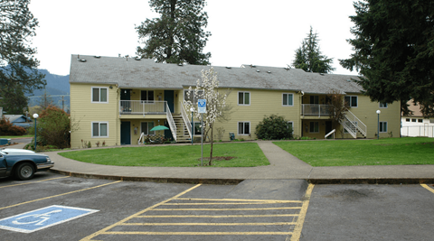 an apartment building in a parking lot with a lawn