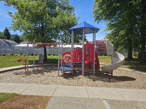 A playground with a blue canopy and red and white slides.