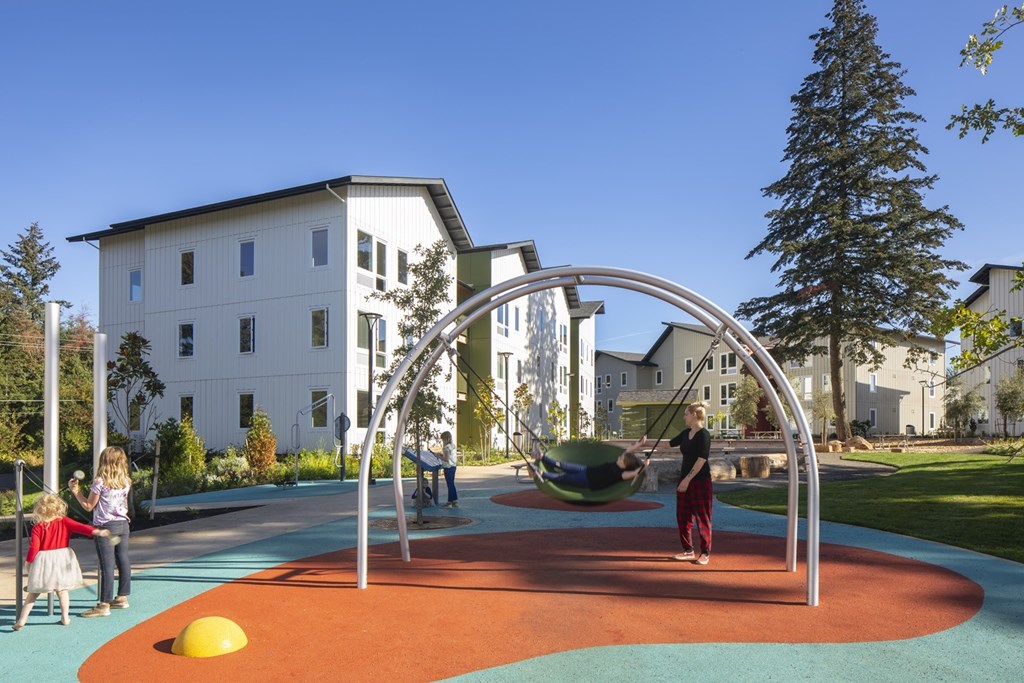 A playground with a swing set and children playing.
