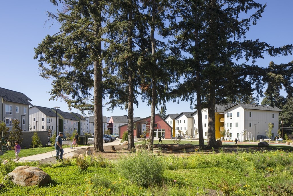 A row of houses with trees in front of them.