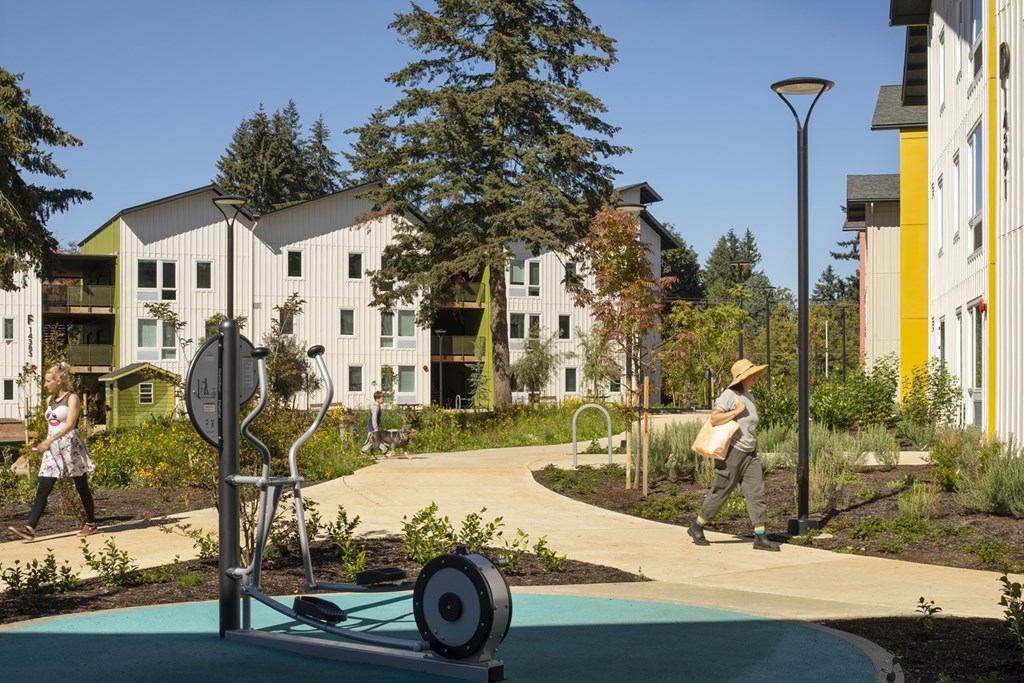 A woman is walking on a sidewalk in front of a white building.