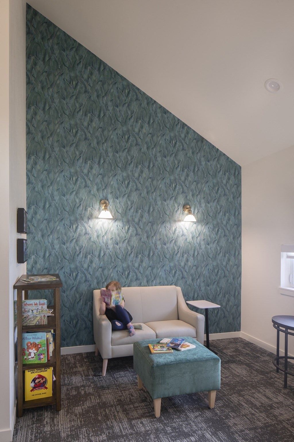 A doll is sitting on a chair in a room with a green wallpaper.