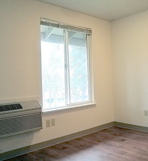 A room with a window and a wall-mounted air conditioner.