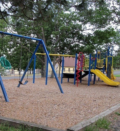 A playground with a blue swing set and a yellow slide.