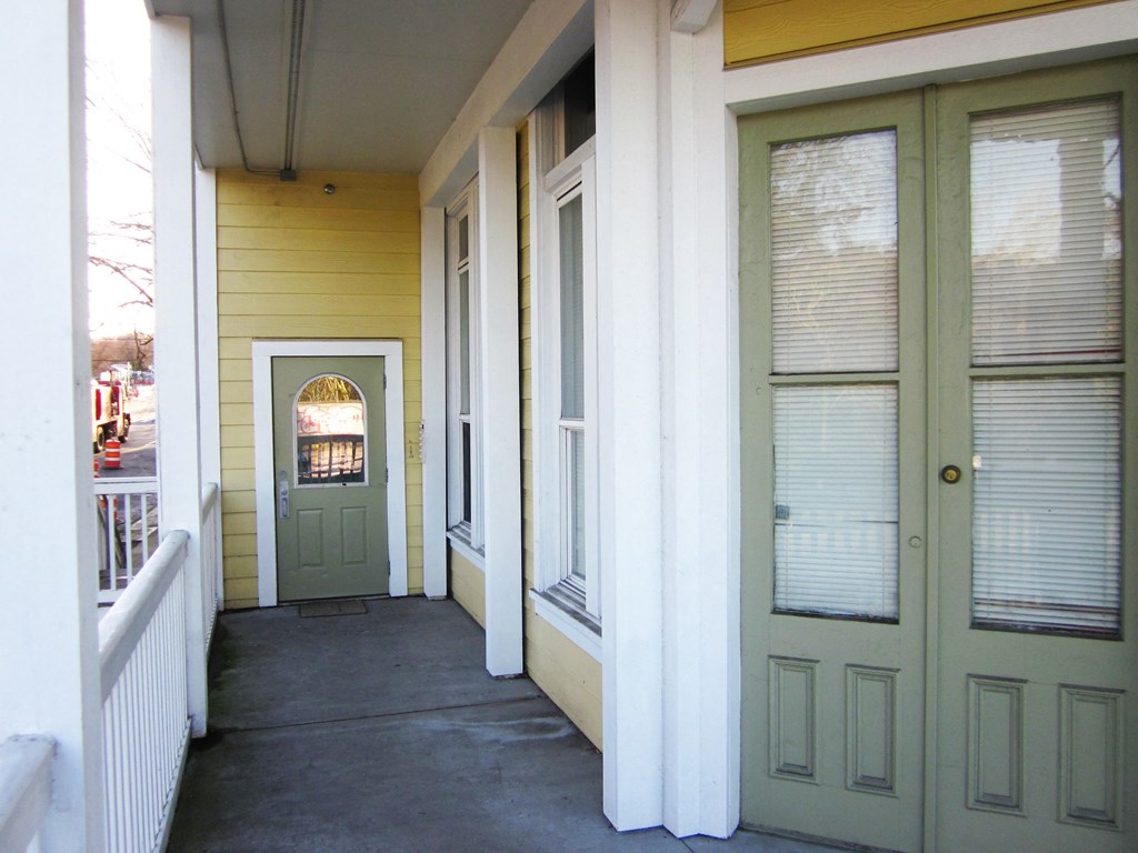 the front porch of a yellow house with a green door