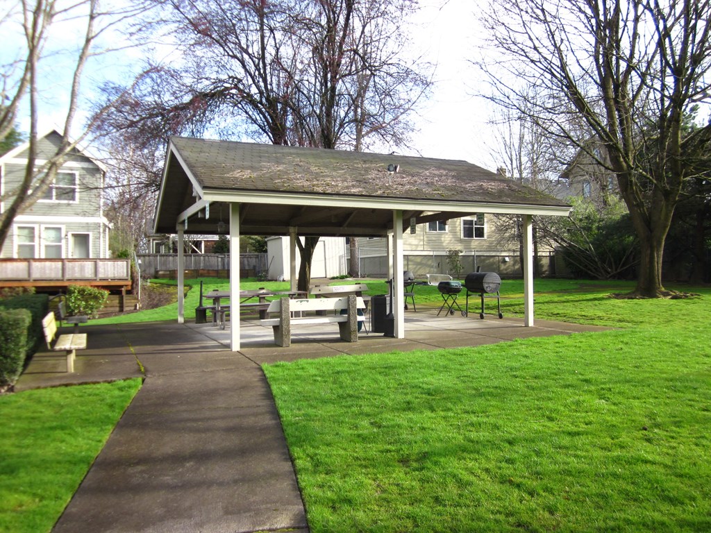 a pavilion with a sidewalk and picnic table in a yard