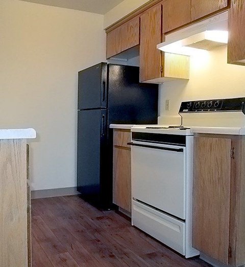 A black refrigerator sits next to a white stove in a kitchen.