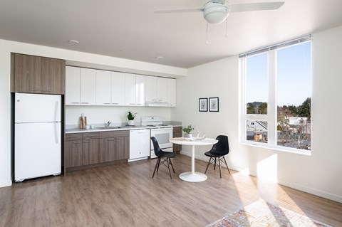 A kitchen with a white fridge, white table and black chairs.
