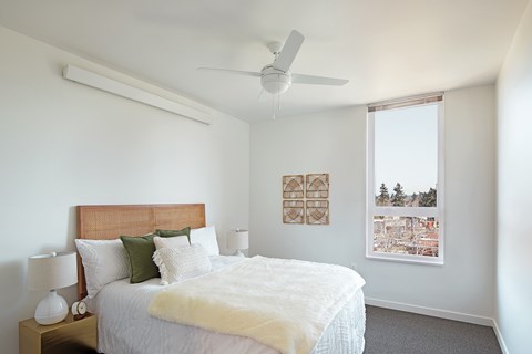 A bedroom with a bed, nightstand, and window.