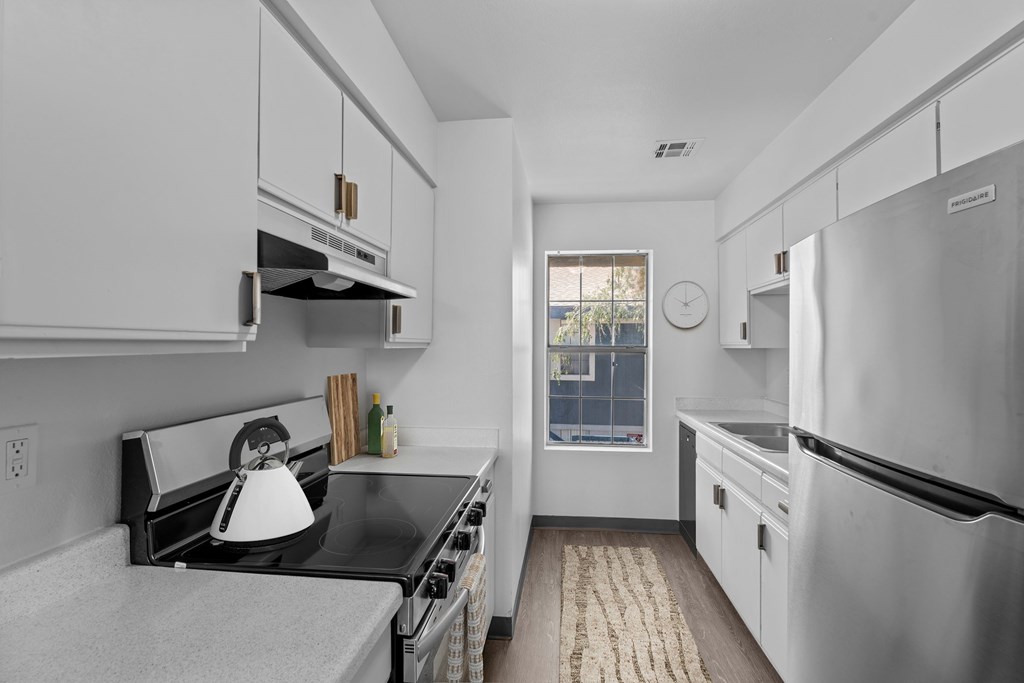A kitchen with white cabinets and a black counter top.