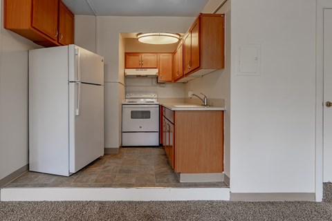A kitchen with a white refrigerator and wooden cabinets.
