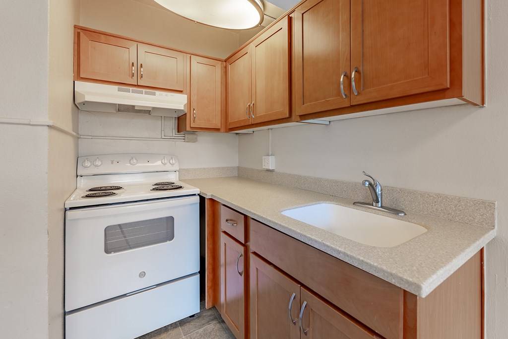 A kitchen with a white stove and wooden cabinets.
