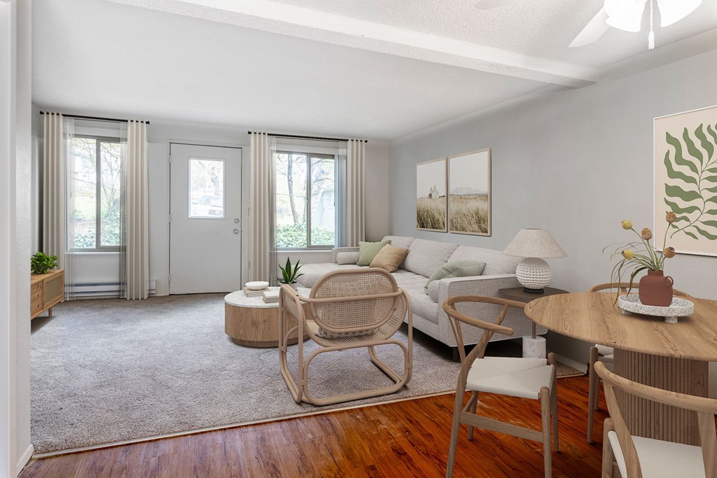 A living room with a white couch, a wooden table, and a rocking chair.