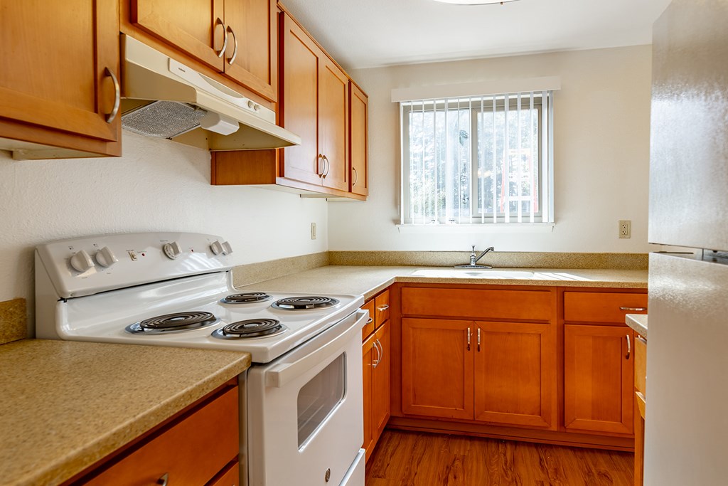 A kitchen with wooden cabinets and a white stove top oven.