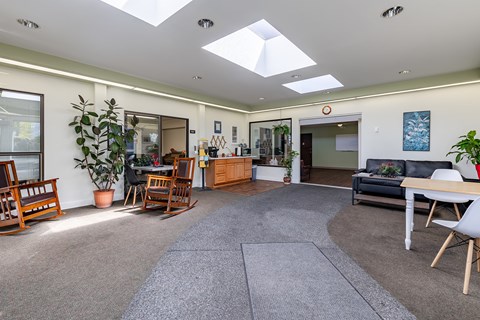 A spacious living room with a grey carpet and wooden furniture.