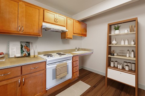 A kitchen with wooden cabinets and a white stove top oven.