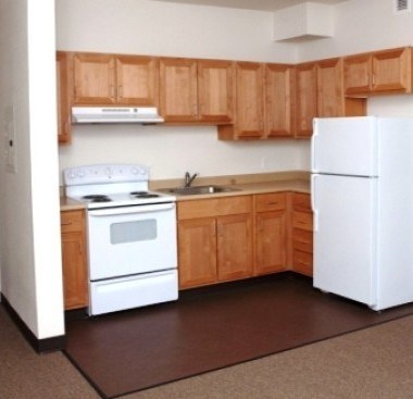 A white refrigerator stands in a kitchen with wooden cabinets.