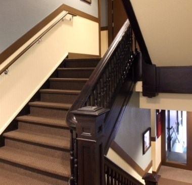 A staircase with a wooden handrail and beige carpeted steps.