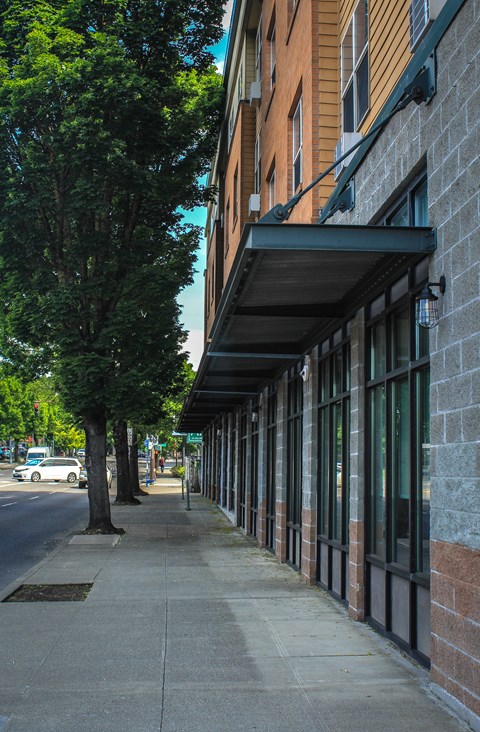 A long building with a black awning sits on a sidewalk.