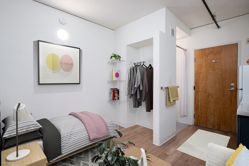 a bedroom with a bed and a closet with clothes hanging on the wall