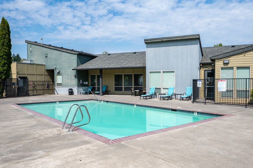 A swimming pool with a diving board in front of a building.